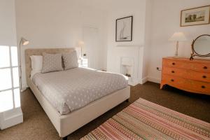 a bedroom with a bed and a dresser and a mirror at Butley Priory Cottage in Woodbridge