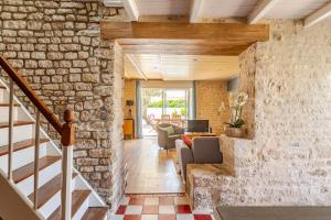 a living room with a stone wall and a staircase at Longère de charme avec piscine, proche océan in Lairoux +41 photos