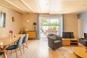 a living room with a table and chairs and a television at Longère de charme avec piscine, proche océan in Lairoux