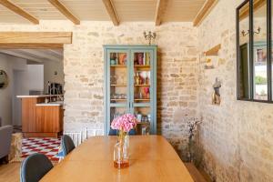 a wooden table with a vase of flowers on it at Longère de charme avec piscine, proche océan in Lairoux