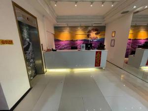 a hallway with a counter in a room with paintings on the walls at Two Chung Hotel in Tucheng