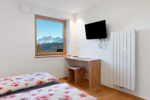 Un dormitorio con una cama y un escritorio y una ventana. en Zolerhof, en Velturno