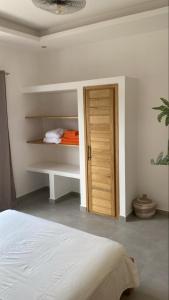 a white bedroom with a bed and a wooden door at Villa Sénégal Elise in Ngaring +1 photo