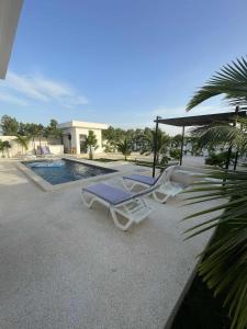 two lounge chairs and an umbrella next to a swimming pool at Villa Sénégal Elise in Ngaring