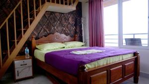 a bedroom with a bed with purple sheets and a staircase at Elora Homes in Vagamon