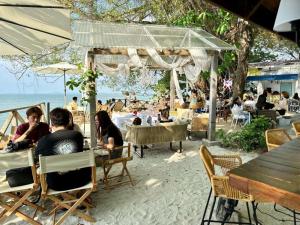 a group of people sitting at tables on the beach at Ardour Lodge "B" Wing in George Town