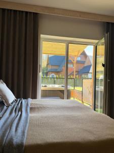 een slaapkamer met een bed en een glazen schuifdeur bij Kominkowy Chill - prywatne zewnętrzne jacuzzi w wybranych apartamentach in Biały Dunajec