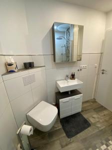 ein weißes Badezimmer mit Toilette und Waschbecken in der Unterkunft Frieslandliebe in Schortens