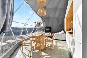 a dining room with a table and chairs and a large window at Sense Resort - Luxury Glamping in Maruszyna