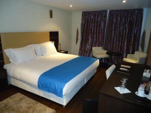 Cette chambre comprend un lit avec une couverture bleue et blanche. dans l'établissement Hotel Emilio Moretti, à Laâyoune