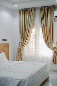 DakibiuにあるHarmonybujのベッドとカーテンのついた窓のある寝室