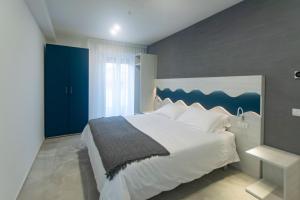 a bedroom with a large white bed with a blue headboard at Residence Flow-R in Riccione +52 photos