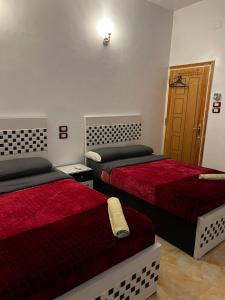 a room with two beds and a door at Mostafa Jamaica guesthouse in Aswan