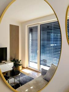 a mirror reflecting a living room with a couch and a table at Apartments Ana in Maribor