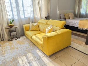 ein gelbes Sofa im Wohnzimmer mit einem Bett in der Unterkunft Cozy Garden Cottage in Johannesburg + 11 Fotos