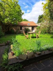 einen Garten mit einem Tisch und Stühlen vor einem Haus in der Unterkunft Clos St Vaast près plage et port in Saint-Vaast-la-Hougue