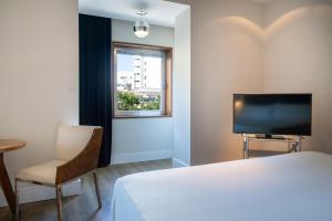 a bedroom with a bed and a tv and a chair at Hotel Palma Avenidas in Palma de Mallorca