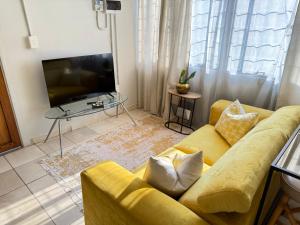 ein Wohnzimmer mit einem gelben Sofa und einem Fernseher in der Unterkunft Cozy Garden Cottage in Johannesburg