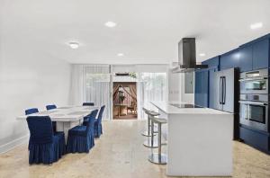 a kitchen with a white table and blue cabinets at Bright Three-Bedroom Modern Apartment with Private Balcony in Hollywood Beach +16 photos