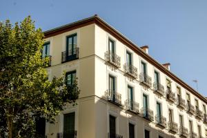 a white building with balconies and a tree at Colectia Stays Atocha in Madrid
