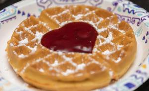 a waffle with syrup on a plate on a table at SureStay by Best Western Charlotte Matthews in Matthews
