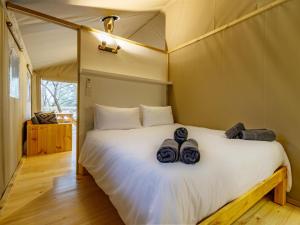 a bedroom with a large white bed with shoes on it at AfriCamps Hoedspruit in Hoedspruit +18 photos