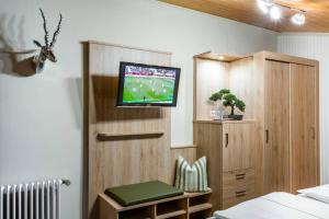 a bedroom with a tv on a wall with a chair at Gasthof Metzgerei Stöberl in Lam