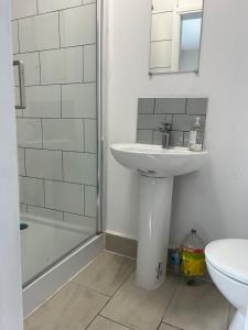 a white bathroom with a sink and a shower at Westfield Street in Saint Helens