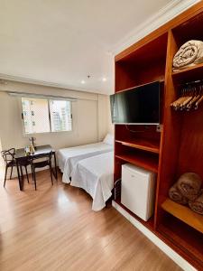 a bedroom with a bed and a table and a television at Flat barra residence-4 pessoas-Fa1204-3 in Rio de Janeiro +75 photos
