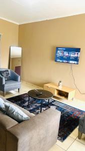 een woonkamer met een bank en een tv aan de muur bij Serene Guesthouse in Manzini