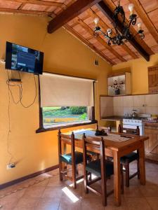 タンディルにあるCabañas Rocasのキッチン(木製テーブル、壁掛けテレビ付) +2枚の写真
