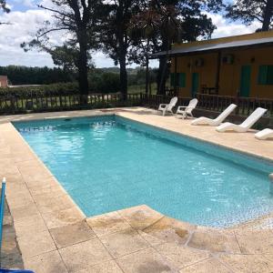 a large swimming pool with chairs and a house at Cabañas Rocas in Tandil