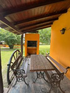 タンディルにあるCabañas Rocasの屋根の下に置かれた木製のテーブルとベンチ