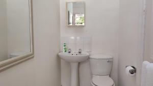 een witte badkamer met een toilet en een wastafel bij Stonehurst Guest House in Kaapstad +52 foto's