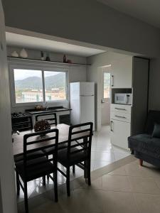 Una cocina con mesa y sillas y un refrigerador. en Frente ao Mar - Acorde Com o Barulho das Ondas apto 10, en Praia Grande