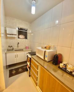 Una pequeña cocina con microondas y fregadero. en Loft p/ casal hidro, café, a/c e vista, en Santo Amaro da Imperatriz
