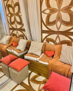 un sofá con almohadas naranjas sentado en una habitación en Loft p/ casal hidro, café, a/c e vista, en Santo Amaro da Imperatriz 1 foto más