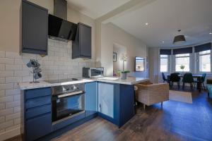 a kitchen with blue cabinets and a living room at The White City Apartment in Oban