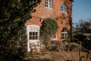 a table and chairs in front of a brick building at Butley Priory Cottage in Woodbridge