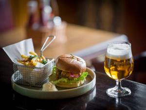 a plate with a sandwich and a glass of beer at Hotel Bishops Arms Lund in Lund
