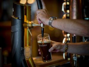 a person pouring a beer into a glass at Hotel Bishops Arms Lund in Lund +39 photos