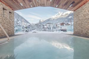 a swimming pool with a view of a snow covered mountain at Premium Activehotel Bergkönig in Neustift im Stubaital