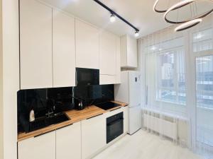 uma cozinha branca com uma pia e uma geladeira em Shabyt Apartments em Astana
