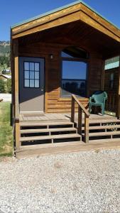 a small cabin with a green chair on the porch at Wonderful Lakefront Cabin near West Yellowstone, Montana in Lakeview +3 photos