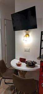 a white table with chairs and a tv on a wall at Comme à la maison in Ducey