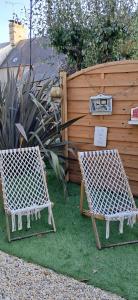two chairs sitting on the grass in front of a fence at Comme à la maison in Ducey
