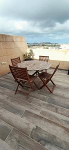a wooden table and chairs on a patio with the beach at Cozy penthouse with Citadel view near to Victoria in Sannat