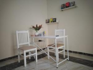a white desk with two chairs and a table and two shelves at Gardenia Hotel in 6th Of October
