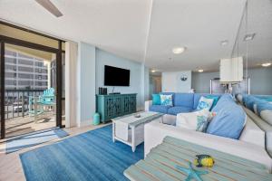 un salon avec un canapé bleu et une télévision dans l'établissement Beautiful & Modern Updated Oceanfront Condo for 10! Sedgefield North 103, à Myrtle Beach