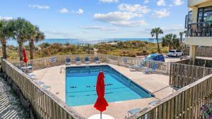 - une piscine avec un parasol, des chaises et l'océan dans l'établissement Beautiful & Modern Updated Oceanfront Condo for 10! Sedgefield North 103, à Myrtle Beach